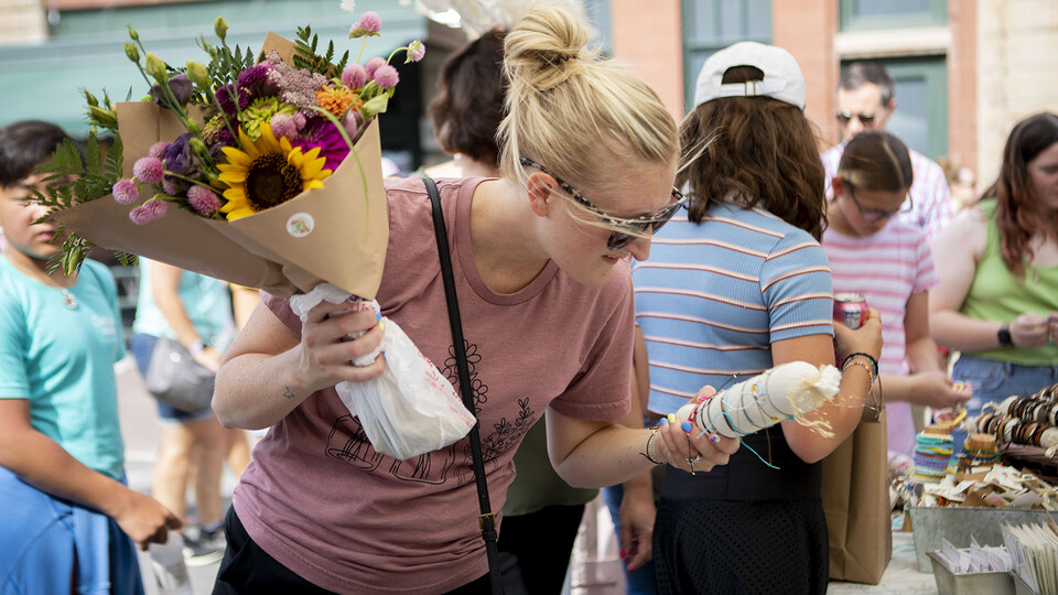 A woman holds two bouquets of flowers as she shops at a farmers market in Lincoln's Haymarket.