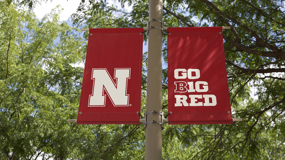 Two red Husker banners on light pole