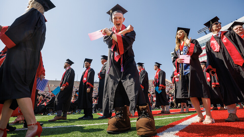 Brendan Kauth-Fisher “throws the bones” while waiting to receive his Bachelor of Science in Business Administration during the undergraduate commencement ceremony May 20 at Memorial Stadium. He has been seen by thousands over the past three years performing as Herbie Husker. Herbies are allowed to reveal themselves at commencement by wearing the mascot’s shoes.