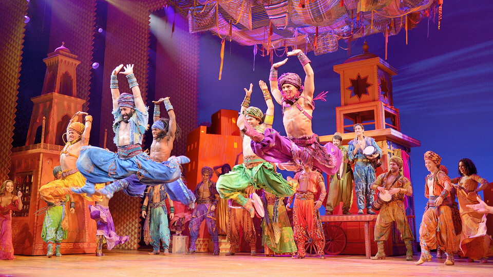 Five men in Arabian garb leap through the air in a market in Disney's "Aladdin."
