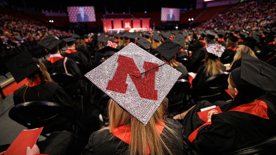 A red Husker N adorns a graduate's mortar board as the graduates watch the December 2022 commencement ceremony at Pinnacle Bank Arena.