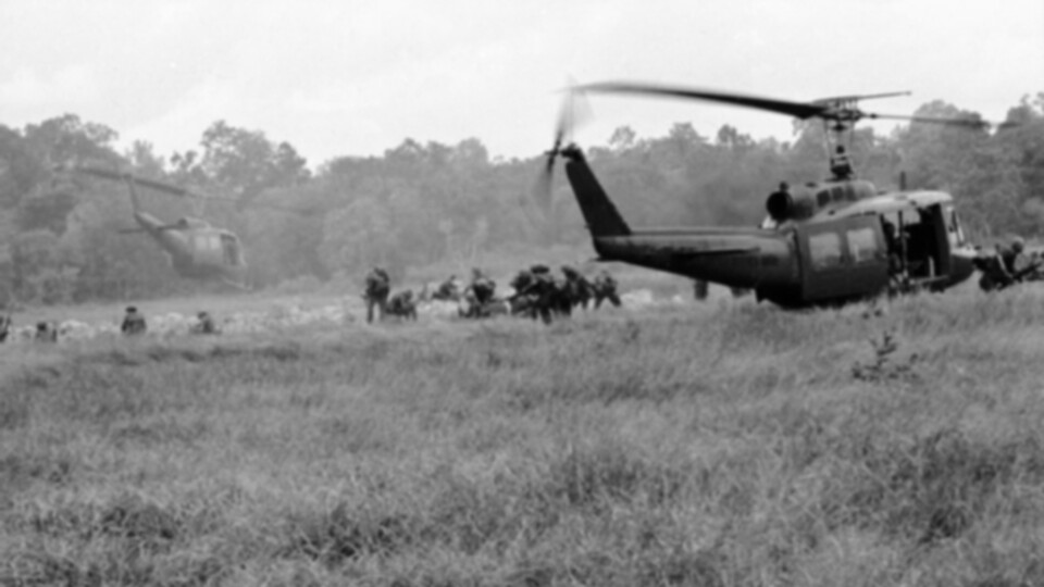 Black-and-white photo of U.S. troops near two helicopters in Vietnam