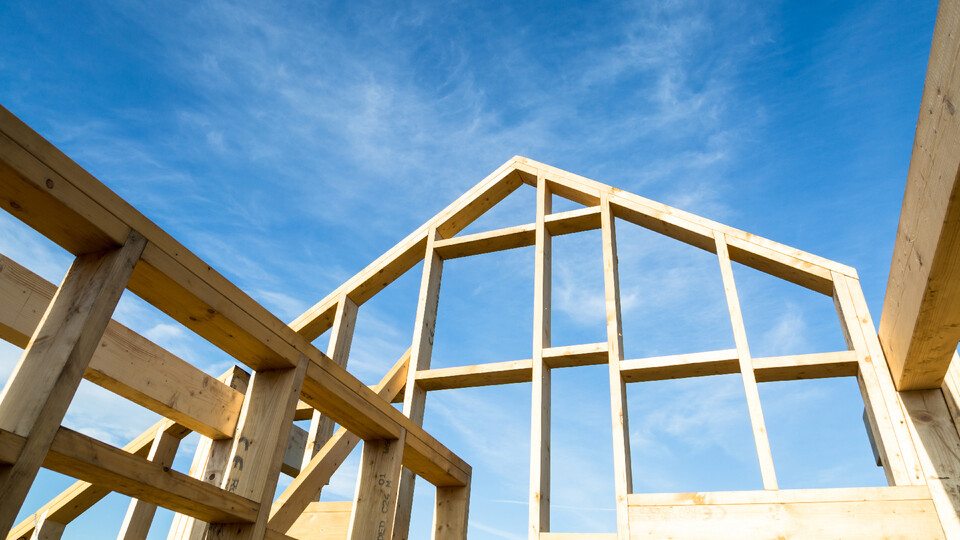 The frame of a house against a blue sky with wispy clouds