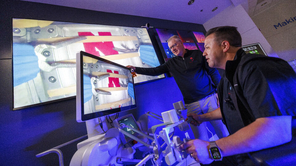 Nebraska Engineering professor and Virtual Incision co-founder Shane Farritor watches as Dr. Michael Jobst uses surgical controls in front of two video screens.