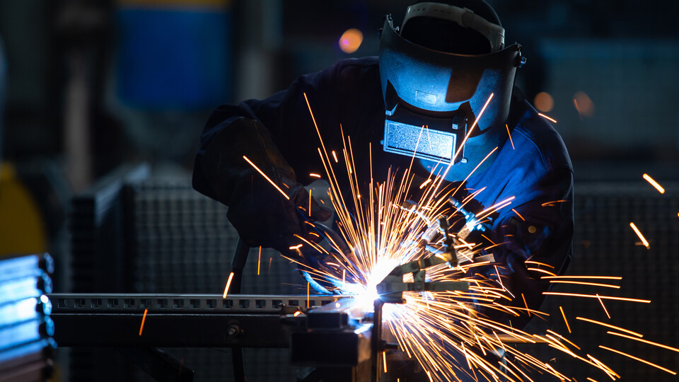 A welder in a mask throws sparks.