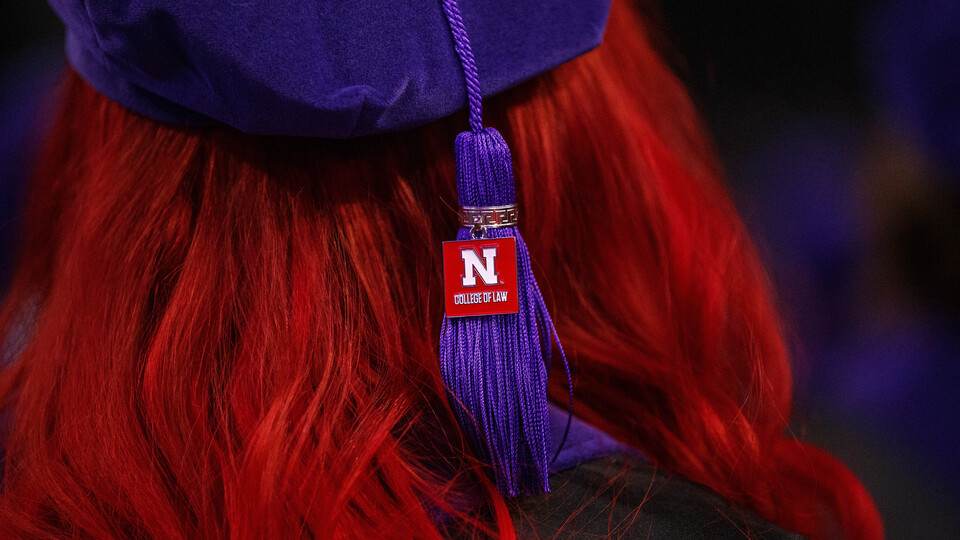 Close-up of a graduate's purple tam and tassle with a "College of Law" tag