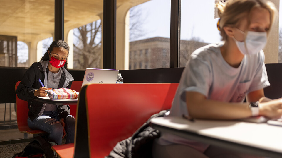 Students Gabriella Silva (red mask) and Zoe Keese (white mask) study at the tables in the sun lit lobby inside Hamilton Hall during the spring 2021 semester. The university will open the spring 2022 semester on Jan. 18 with updated COVID-19 protocols.