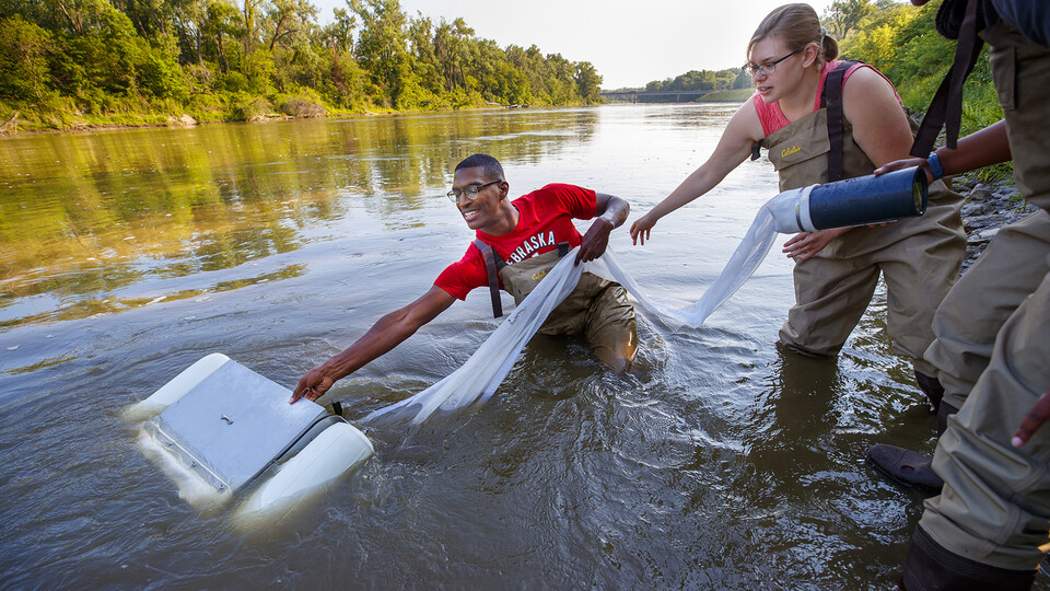Seth Caines, Meredith Sutton and Moriah Brown stretch out to use a floating sieve to gather a water sample in the Elkhorn River on July 2. The trio is working with Shannon Bartlet-Hunt, department chair and professor of civil and environmental engineering, researching textiles as a source of microplastic fibers found in streams across the Cornhusker State.