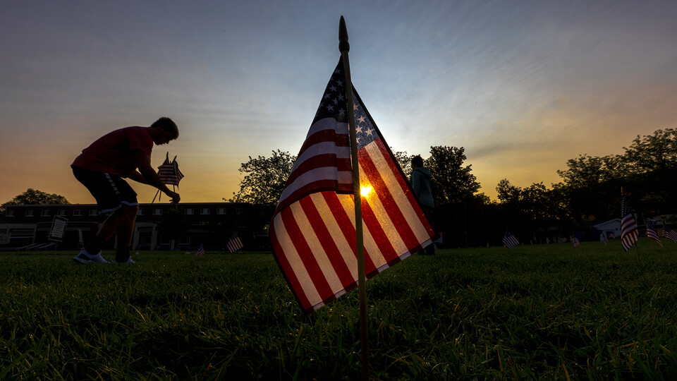 The rising sun shines through a flag placed by a student in the grass north of the Nebraska Union. The flags were placed as part of a 20-year memorial to the attacks of Sept. 11, 2001.