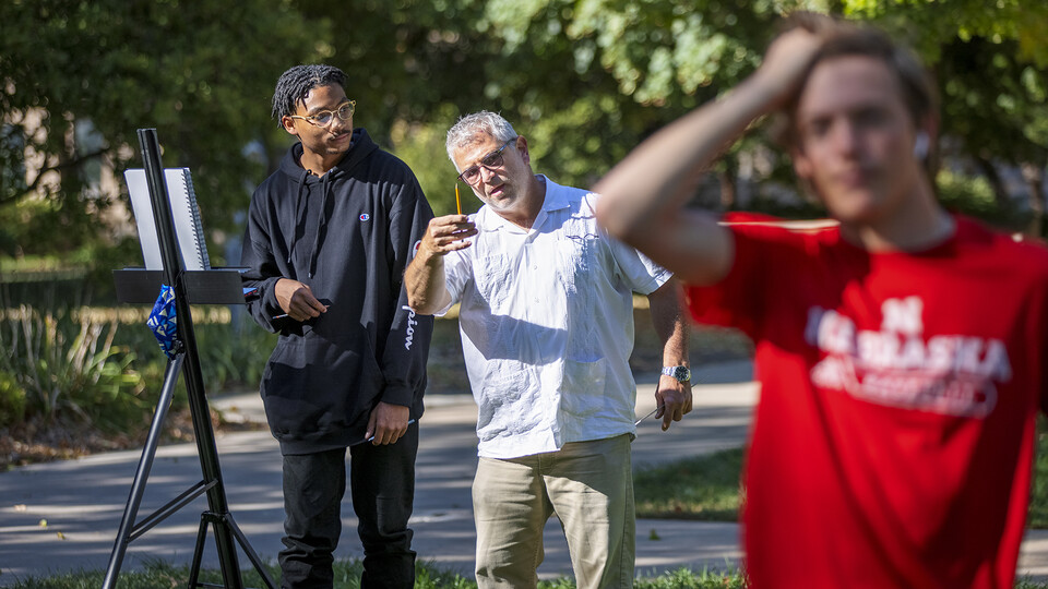 Chip Stanley (middle) works with Adham Westbrook (left), a first-year architectural engineering major, on perspective and height as part design drawing course assignment. The class met outside this week, taking advantage of beautiful fall weather.