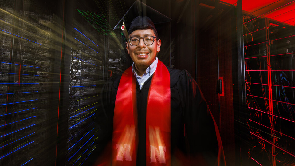 Bryan Chavez stands in front of a super computer. 