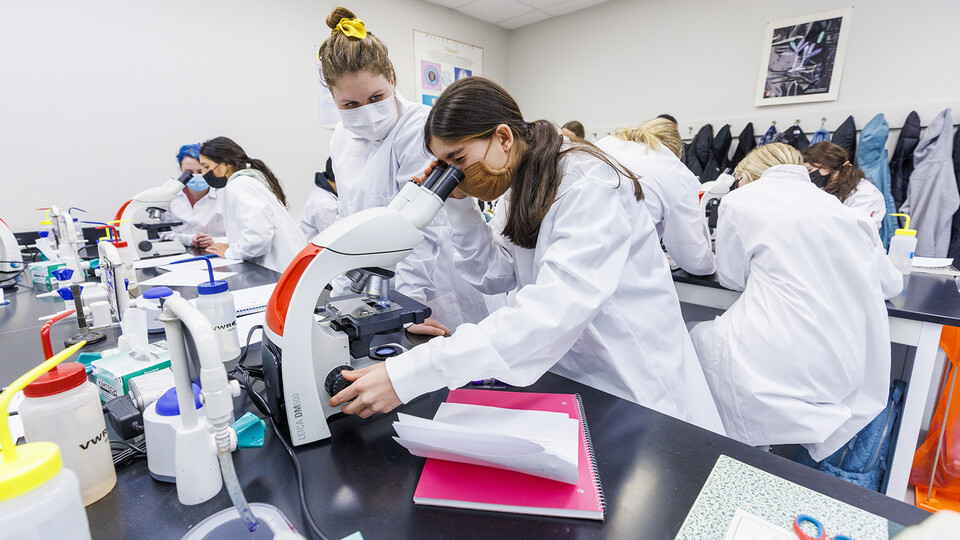 Students look into a microscope during a microbiology lab on Jan. 24.