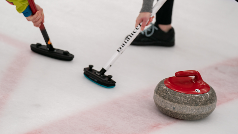 A curling stone and brooms.