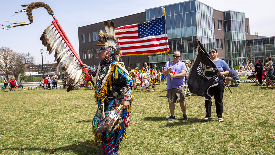 Scott Aldrich, head man dancer (left) leads the colors into the circle at the start of the UNITE powwow on April 23.