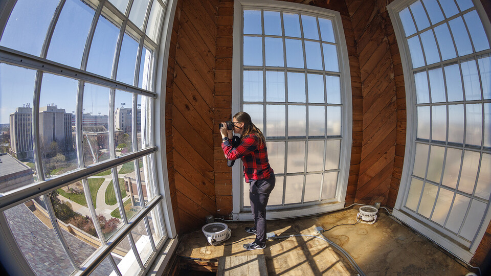 Erin Colonna, graphic designer with the University Libraries, documents signatures on the walls inside the Love Library cupola. A summer restoration will repair damage to the exterior of the cupola.