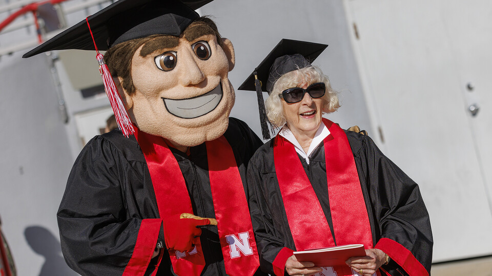 Carol Livingston poses with Herbie Husker after receiving her degree in Memorial Stadium on May 14.