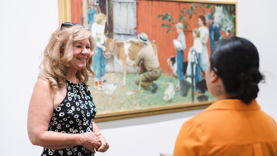 Peggy Montarsi talks with Evelyn Mejia, a Lincoln Journal Star reporter and a broadcasting major, in the Sheldon Museum of Art. Montarsi visited campus to see the Sheldon's Norman Rockwell painting, which features her family members.
