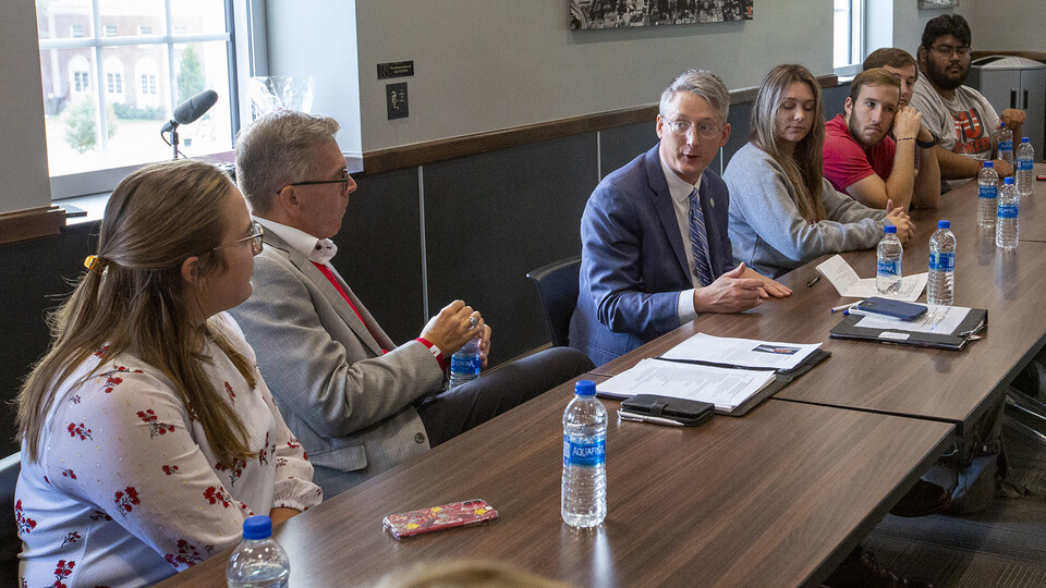 James Kvaal (center, in blue suit) talks with students and Chancellor Ronnie Green during his visit to campus on Sept. 16. Kvaal, who is from Massachusetts, often visited his grandparents in Omaha as a youth, and attended Husker football games.