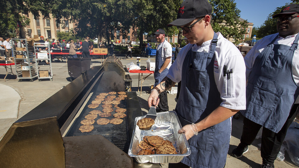 Drake Wiggins, a worker with Dining Services, prepares hamburgers during the cook-out. Nearly 1,000 employees were expected to participate in the event, which followed the State of Our University address.