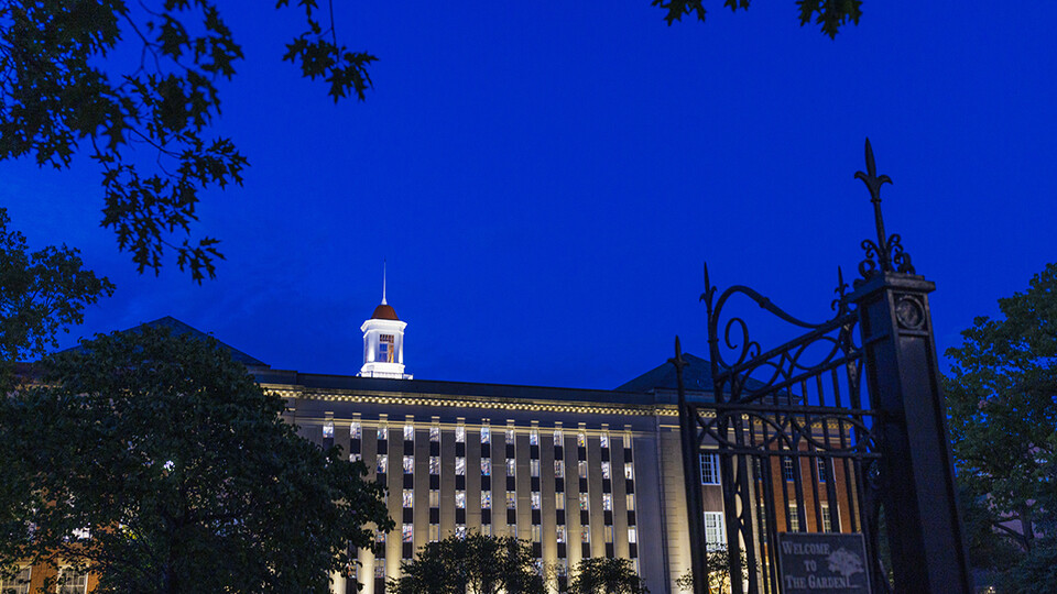 Love Library is illuminated against the sky at dusk.