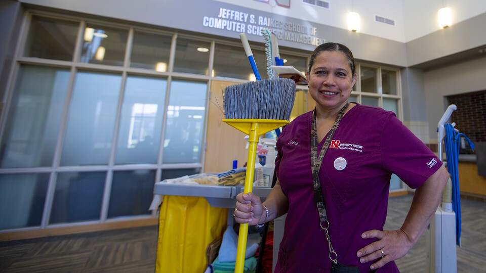 University Housing's Saira Bautista de Preciado stands proudly, holding a broom, in Kauffman Hall. Bautista de Preciado has worked as a custodian in the Raikes School for 10 years. She recently was awarded an Employee Service Award for her dedication to the university.