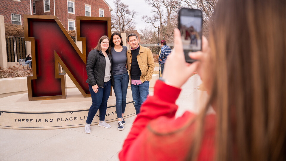 A prospective Husker and her family poses in front of the iconic "N" statue outside the Wick Alumni Center during Admitted Student Day on March 25.