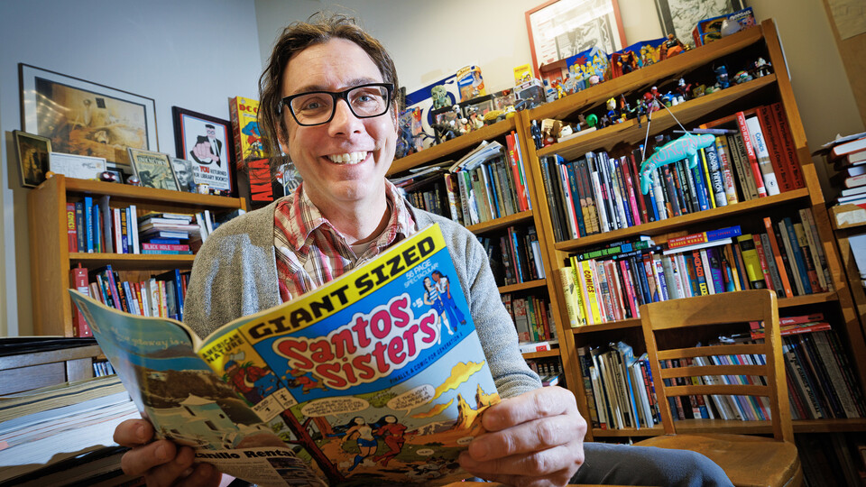 Richard Graham, Associate Professor of University Libraries, sits in his office overflowing with comic culture
