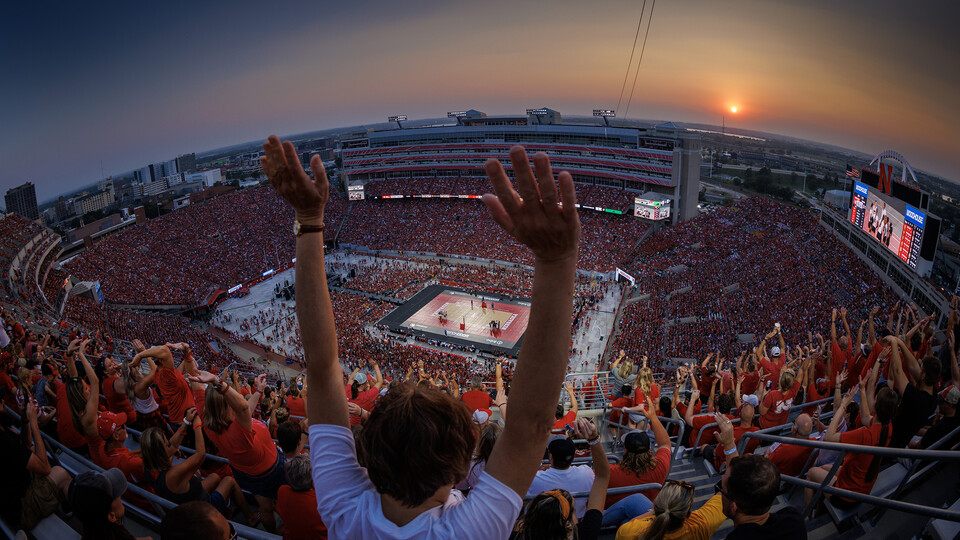 The crowd does the wave during a time out as the sun sets over Memorial Stadium.