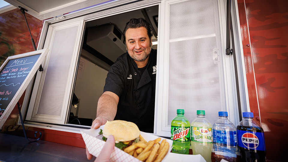 Octavio “Otto” Meza, production manager for Housing and Dining Services, waits on customers at the Harper's Smokehouse Food Fruck parked outside Avery Hall.