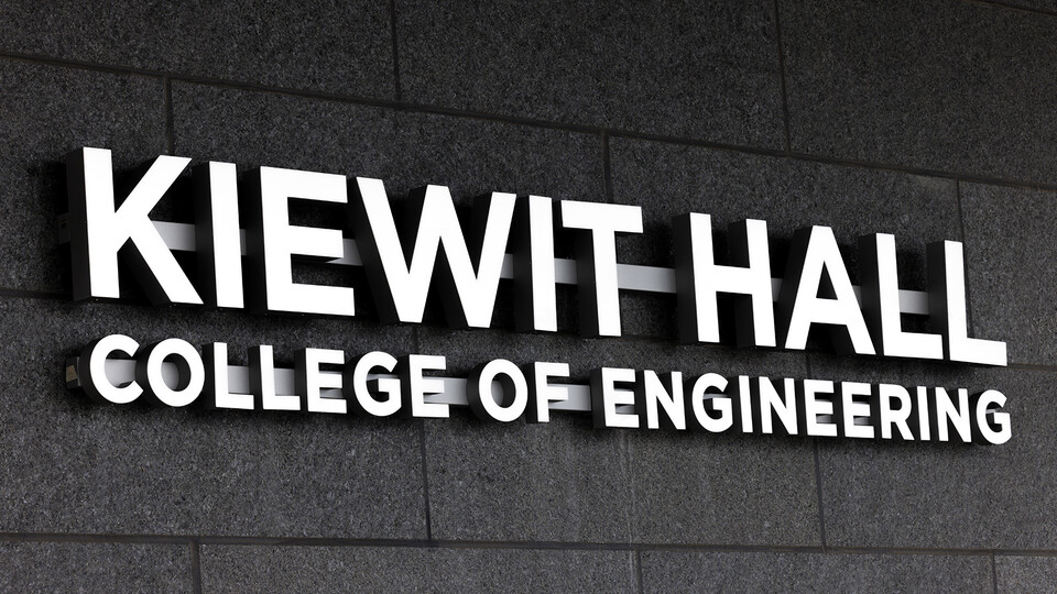 Silver letters spell out Kiewit Hall on dark stone as part of the entry to the new engineering building.