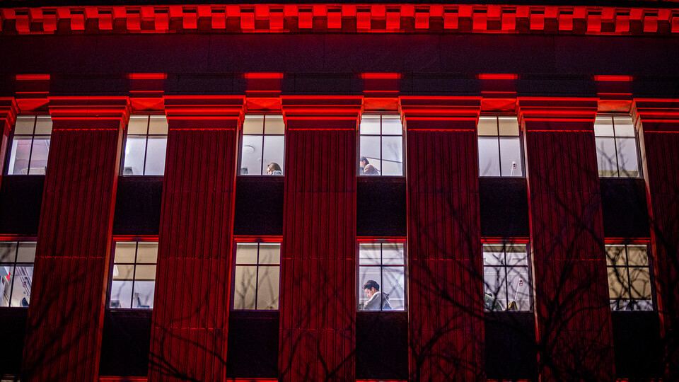 Students study inside Love Library as red light reflects off the building's southern facade.