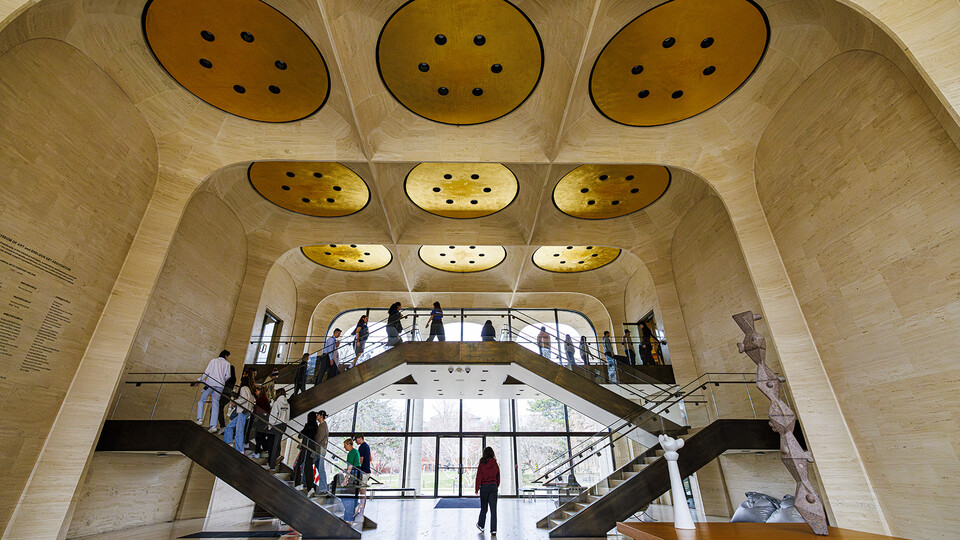 Gold ceiling circles shine as visitors walk through Sheldon Museum of Art's Great Hall.