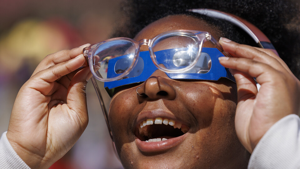 Samya Lee, a freshman from Omaha, smiles as she can see the eclipse by holding her eyeglasses over the eclipse glasses.