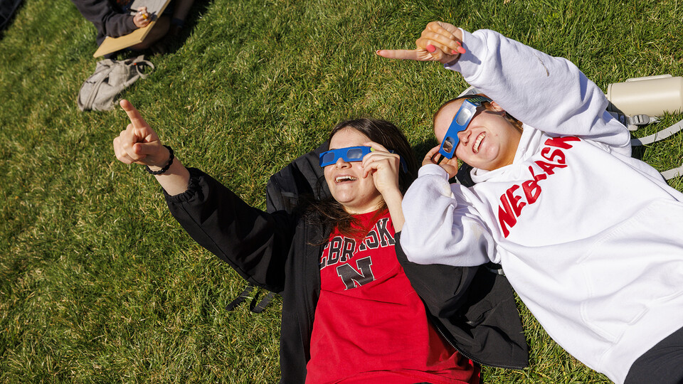 Julia Connealy and Jesse Trout react as they watch the eclipse on the Meier Commons grass north of the Nebraska Union.