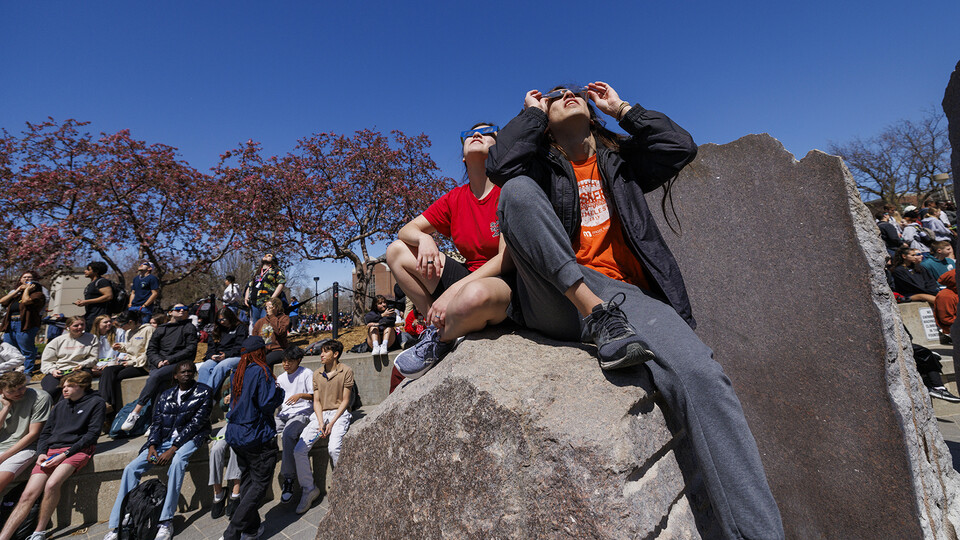 Students watch eclipse progress on the rocks of Broyhill Fountain.