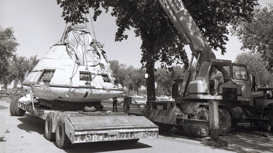 Workers use a crane to install the Apollo 009 capsule on the north side of Morrill Hall in 1972.