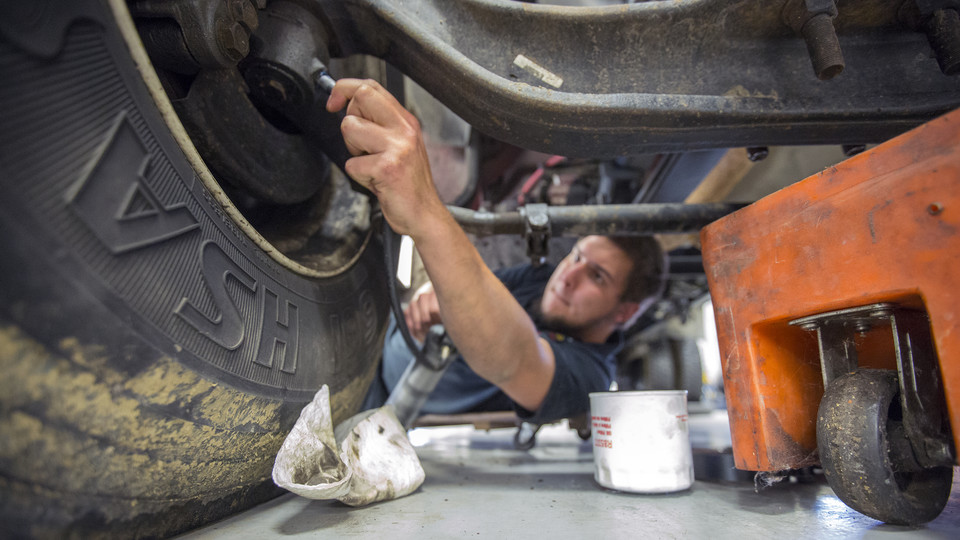 Jacob Green, a mechanic II, lubricates the chassis of a university delivery truck at the Transportation Services garage on City Campus.