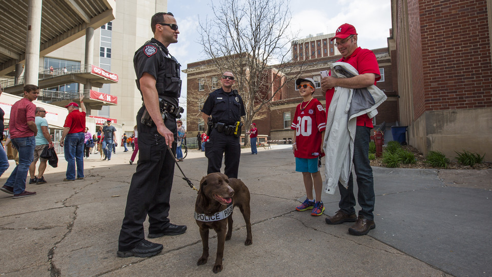 K-9 handler Greg Byelick (left) discusses his new partner, Justice, with Mike Heller (right) and his son Robbie prior to the start of the Huskers' spring football game on April 15. The University Police Department has added two K-9 patrols that will primarily be used for bomb detection.