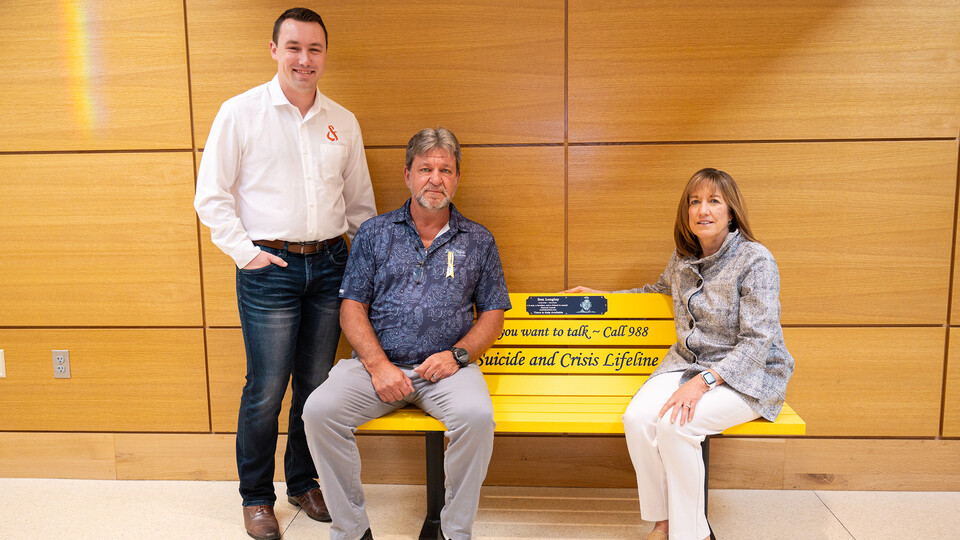 A yellow bench in honor of the late Ben Longley was unveiled in Howard L. Hawks Hall at the College of Business on Sept. 26. Donated by his parents, Paul (middle) and Leigh-Ann Longley, the bench includes the national Suicide and Crisis Lifeline number, 988.
