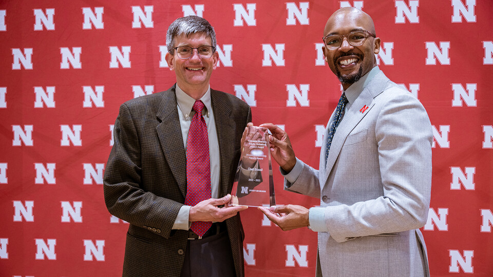 Chad Brassil accepts the Diversity Leadership Faculty award from Marco Barker, vice chancellor of diversity and inclusion.