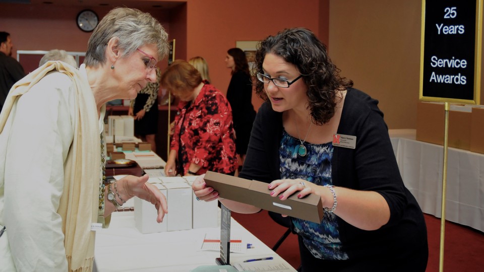 Marcy Neeman (right), a facilitator for Human Resources, helps Christine Marvin, associate professor of special education and communication disorders, find her 25-year service award during the 2013 ceremony.