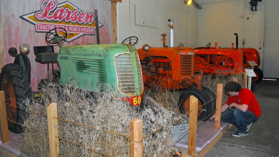 Lance Todd, manager of exhibits at the Lester F. Larsen Tractor Test and Power Museum, installs grass in the new exhibit. The project showcases an Oliver 60 and SC-Case in a setting that resembles an overgrown grass area behind a barn. 