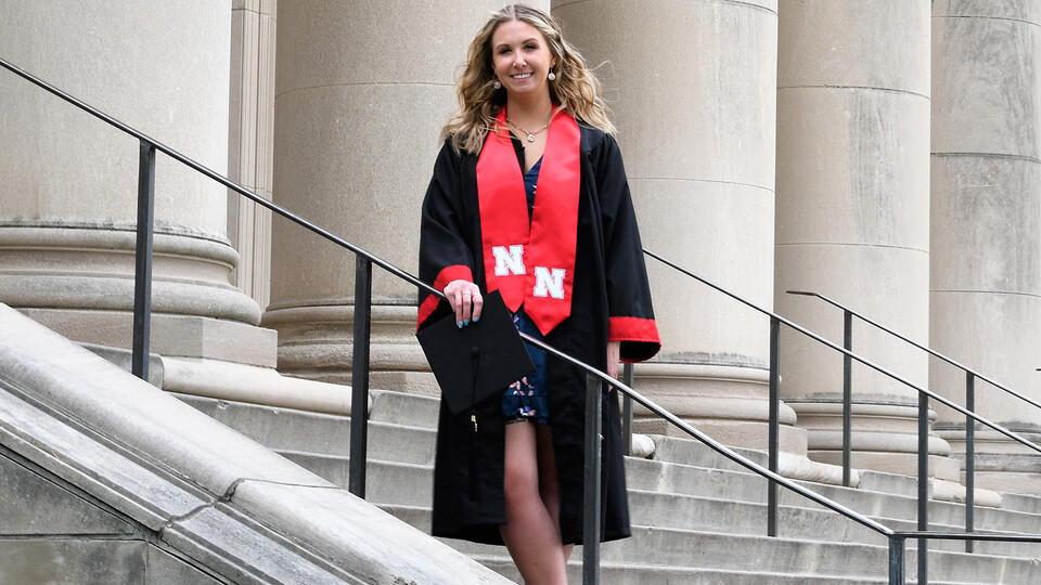 Emily Stratmoen in graduation gown on university steps