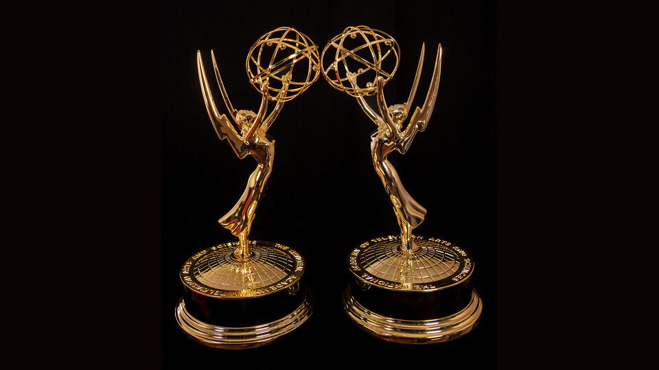 Two Emmy Award statuettes on black background