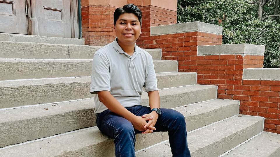 Edgar Román sitting on the steps of Architecture Hall