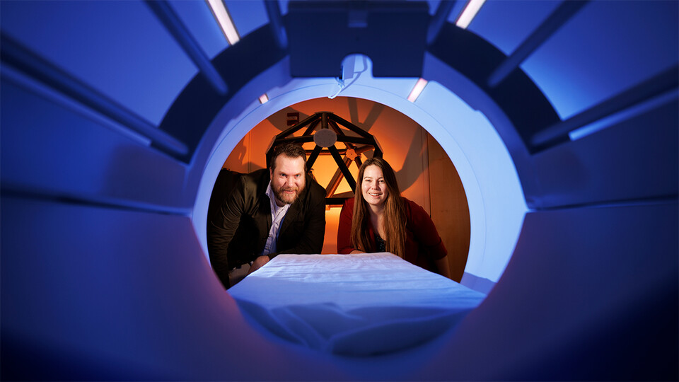 Doug Schultz and Heather Bouchard peer into the chamber of an MRI machine