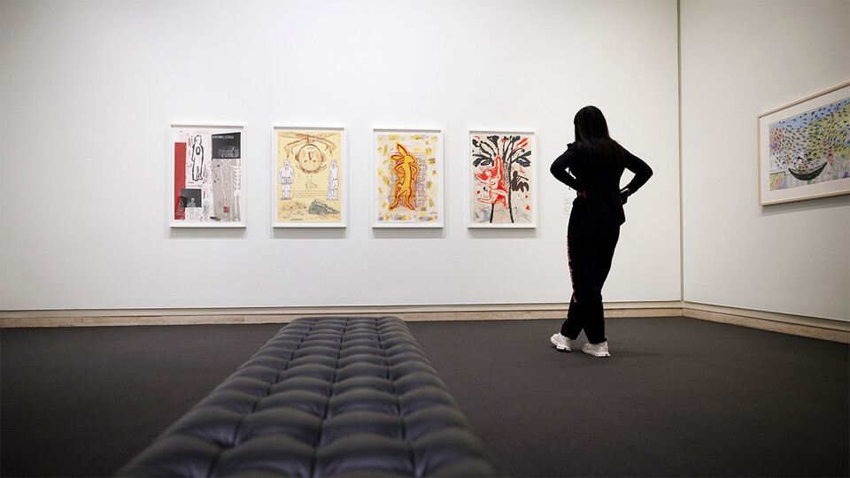 A student looks upon four paintings at Sheldon Museum of Art