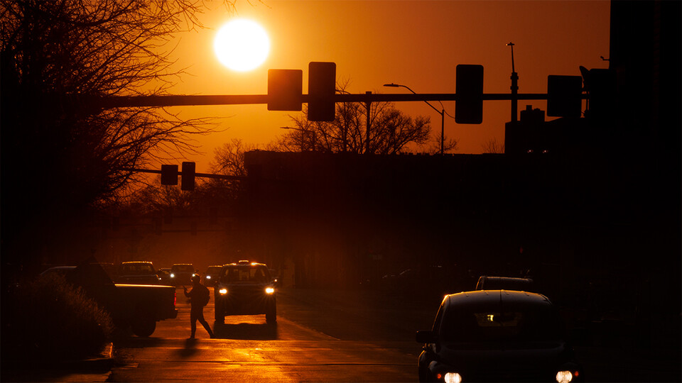Vehicles on Q Street are silhouetted against the rising sun