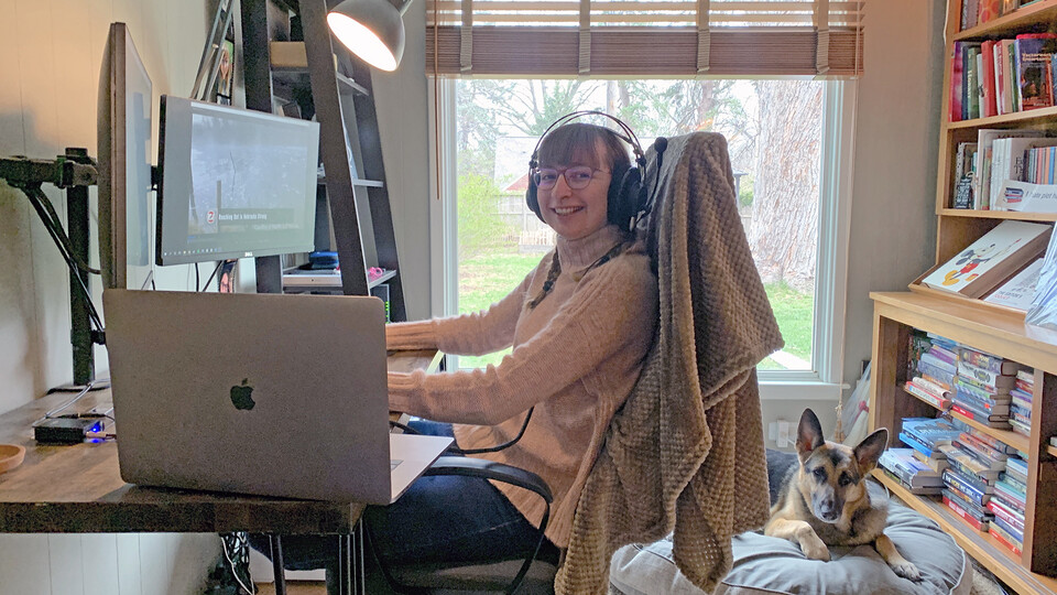 Mattie McIntosh sits in her home office with Zelda, a German shepherd. The video editor for IANR Media is this week’s winner of the Husker Home Office honor.