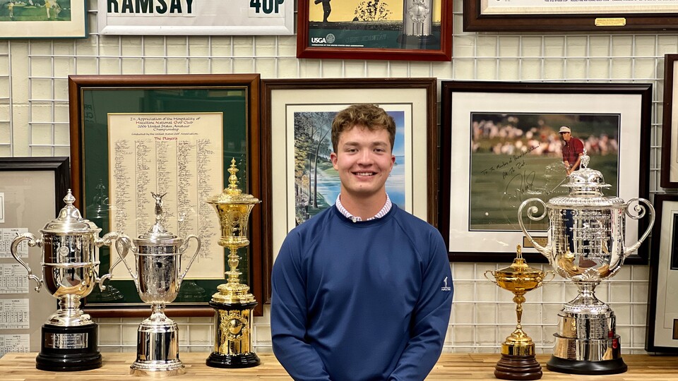 Koby Head stands in front of trophies from tournaments hosted at Hazeltine National Golf Club. Head gained career experience through a 16-week internship at the club..